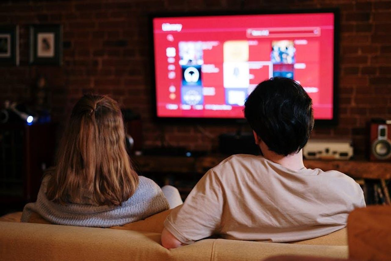 Rinnovo_della_serie_Matlock_per_la_seconda_stagione_C4lnA4CZYr - Confidenze24 Source: cottonbro studio - pexels - A couple enjoys streaming shows on a large TV in a cozy, brick-walled living room.