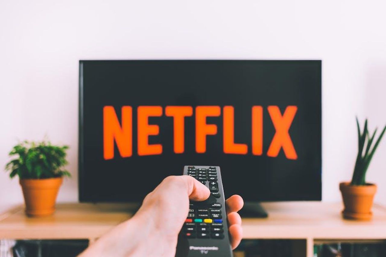 Rinnovo_di_Tracker_per_la_Terza_Stagione_FyBZbPcYc9 - Confidenze24 Source: freestocks.org - pexels - A hand holding a TV remote in front of a screen with Netflix, perfect for streaming and movie night themes.