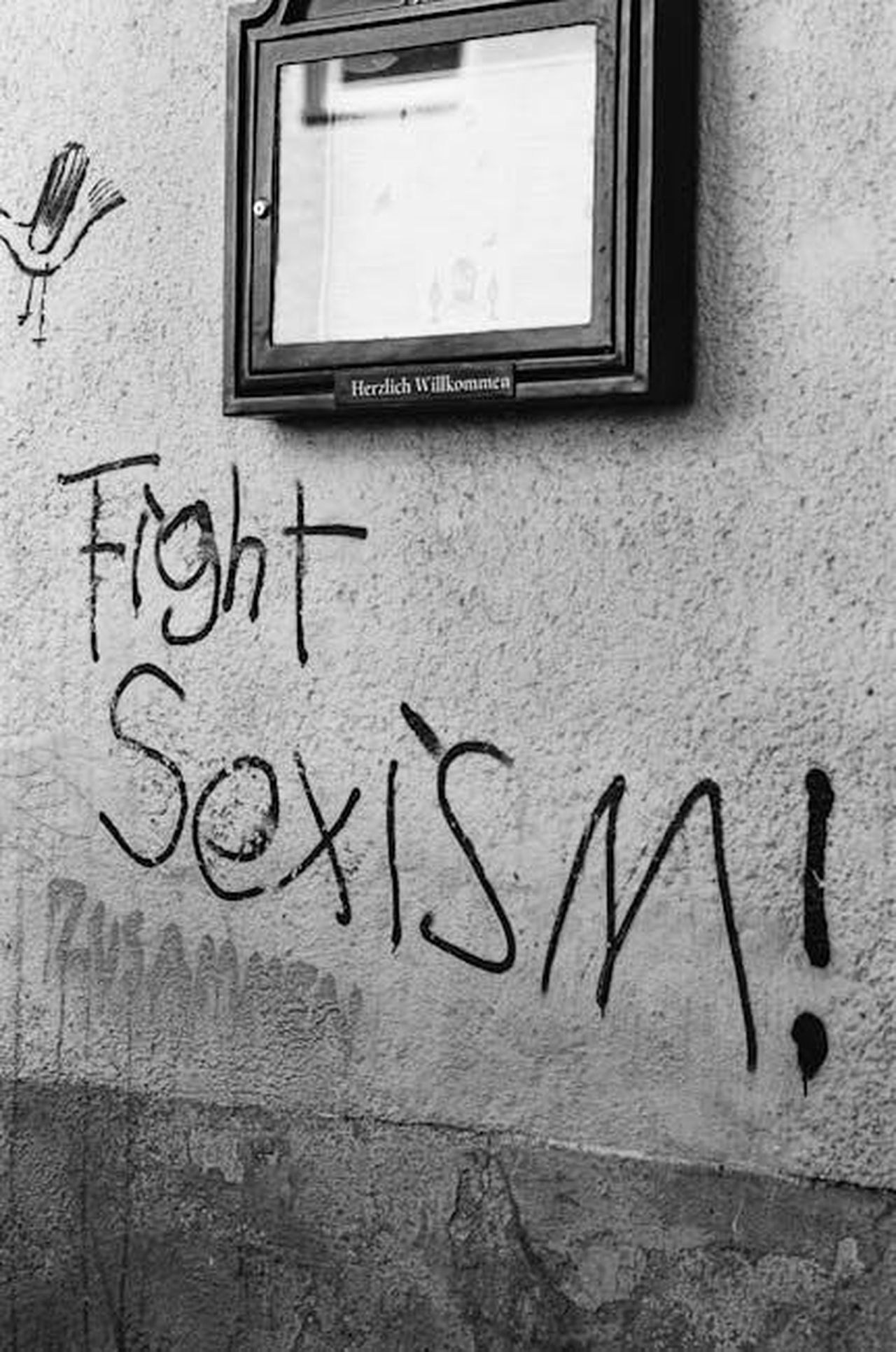 Rissa_con_un_senzatetto_6m8BWpo7K2 - Confidenze24 Source: Markus Spiske - pexels - Black-and-white photo of graffiti urging to fight sexism on a street wall.