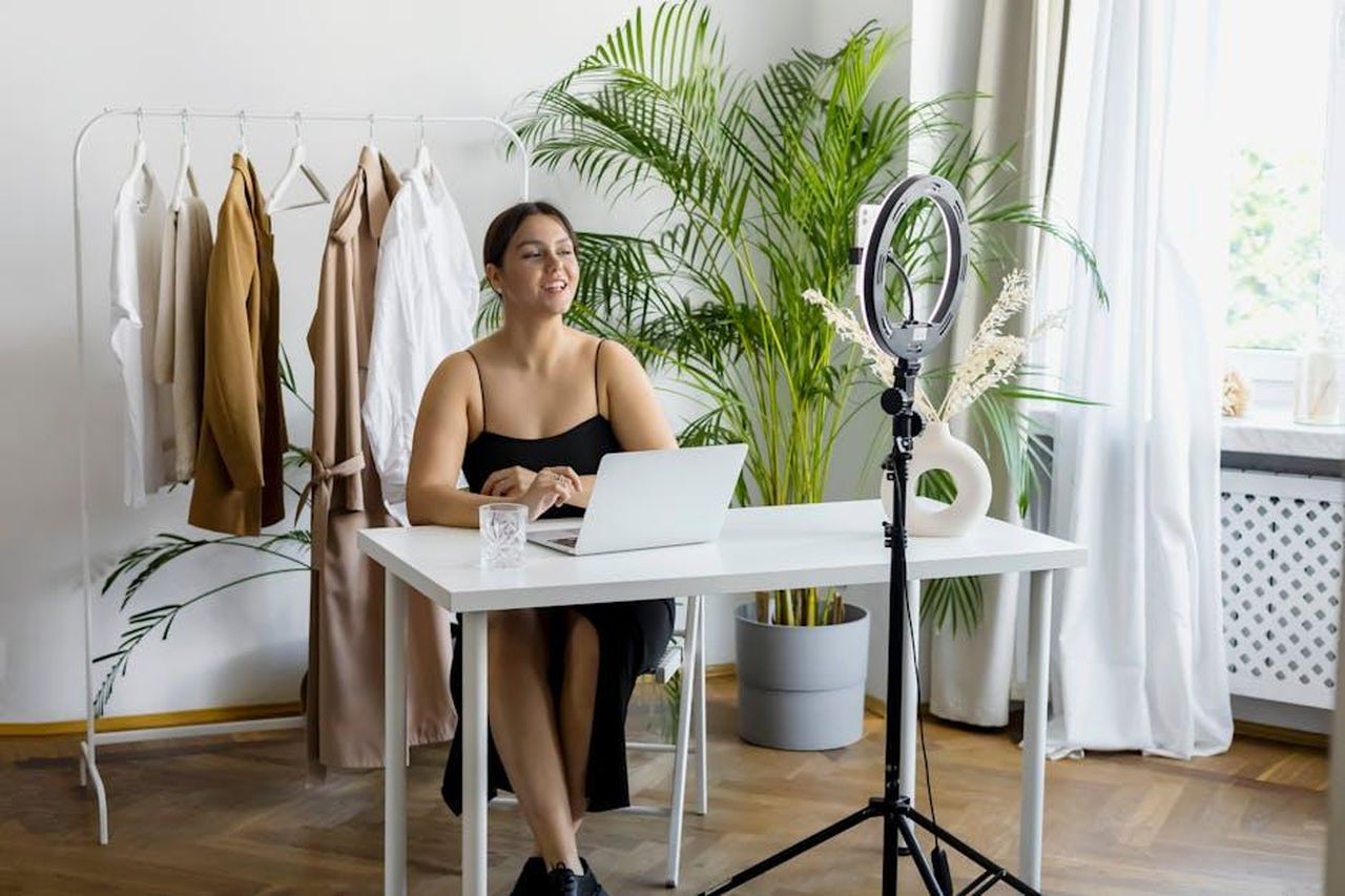 Ritorno_nel_mondo_degli_influencer_EBwbFJuTwj - Confidenze24 Source: Anna Nekrashevich - pexels - Woman recording a video at home with laptop and ring light, fashion outfits in the background.