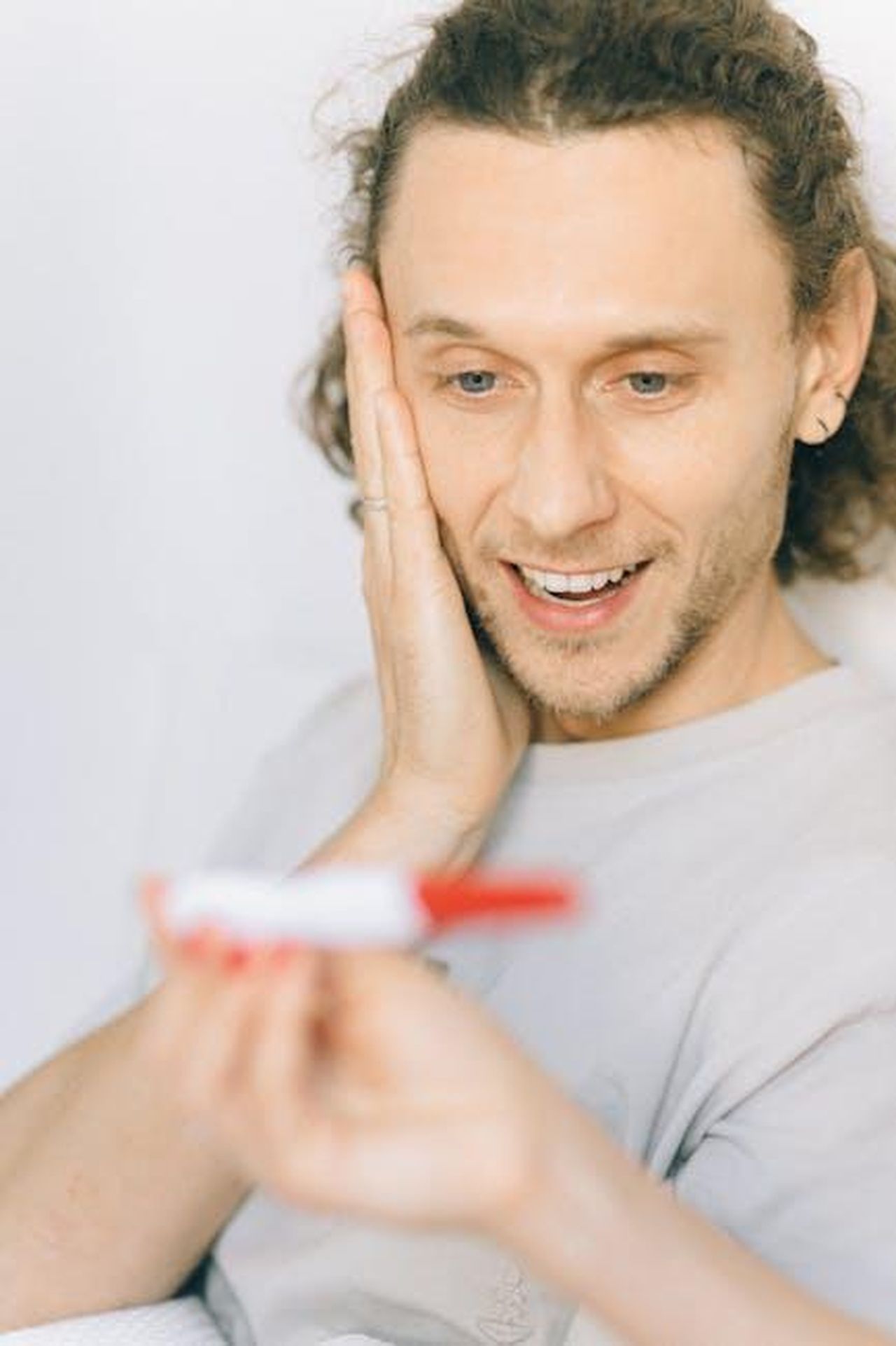Rumori_su_un_secondo_figlio_Mbf3IMw3fb - Confidenze24 Source: Nataliya Vaitkevich - pexels - A happy man with curly hair excitedly reacting to a positive pregnancy test.