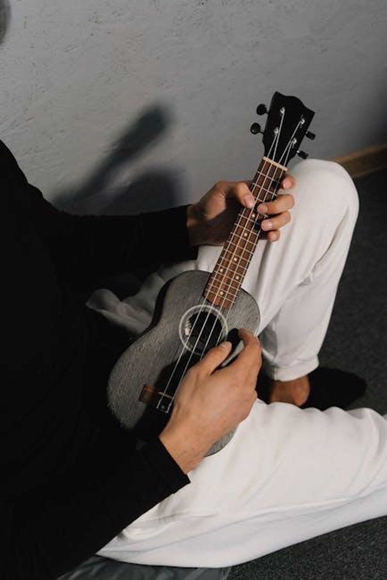 SAINt_JHN_e_i_problemi_di_salute_mentale_nella_sua_musica_fFCQsBLOxL - Confidenze24 Source: Mikhail Nilov - pexels - Close-up of a person playing a ukulele indoors, wearing black and white attire.