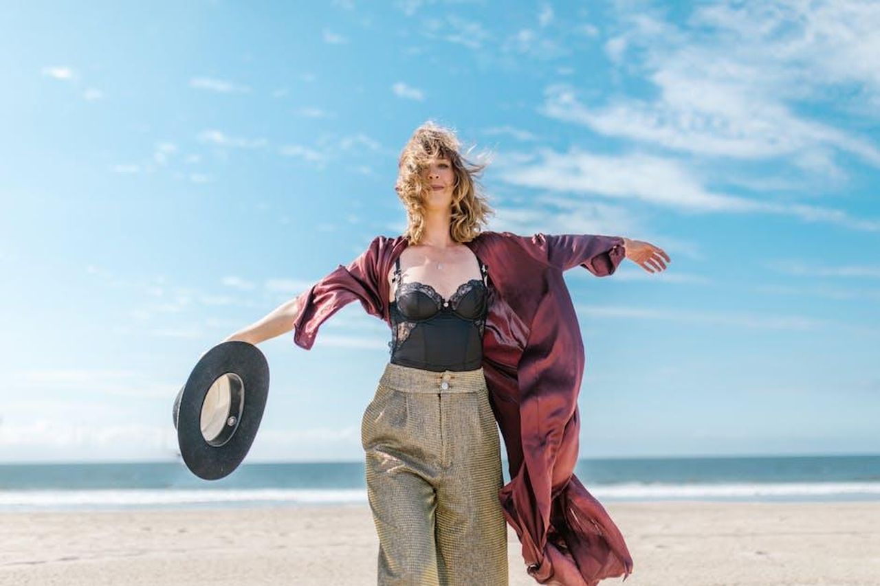 Sagittario_22_Novembre__21_Dicembre_199SXeYi2W - Confidenze24 Source: RDNE Stock project - pexels - A woman in stylish attire enjoying a sunny day at the beach, exuding freedom and joy.