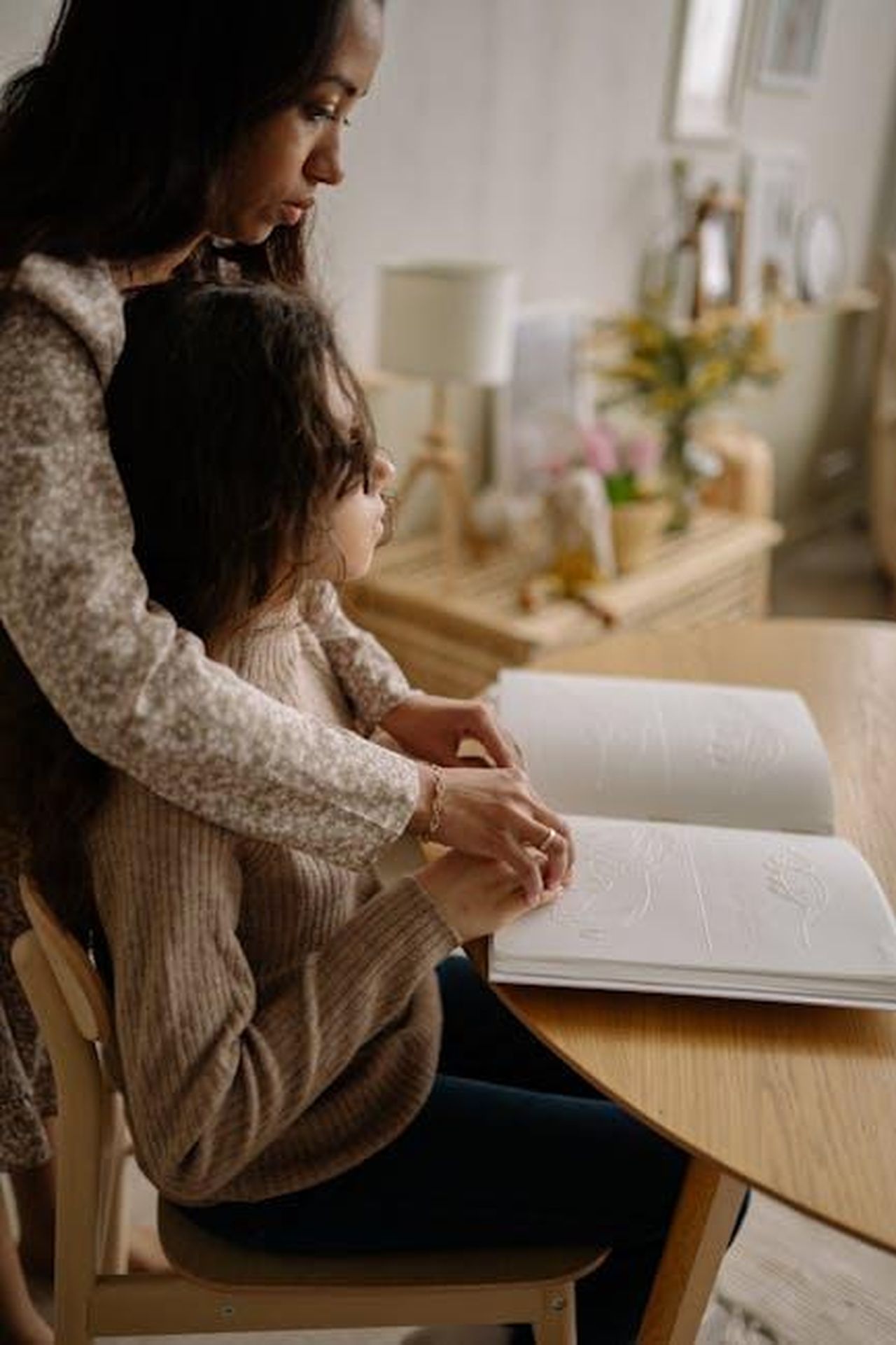 Sara_smentisce_le_voci_di_un_fidanzamento_con_Joey_3HFRVgjvOf - Confidenze24 Source: Yan Krukau - pexels - A woman guides a young girl reading a Braille book at a wooden table indoors.