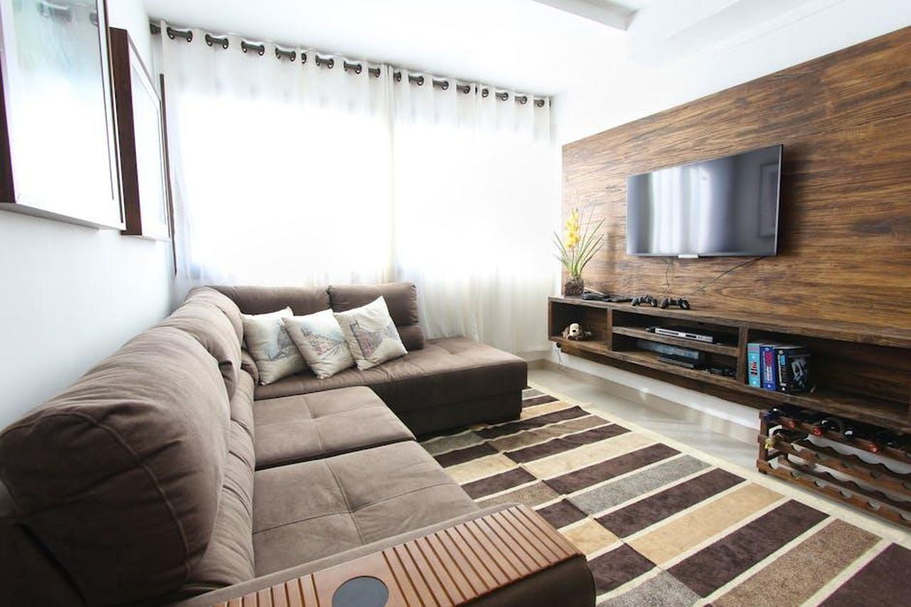 Serate_romantiche_a_casa_la_loro_routine_C1HlHa6l9f - Confidenze24 Source: Pixabay - pexels - Stylish modern living room featuring a brown sofa, wall-mounted TV, and interior decor.