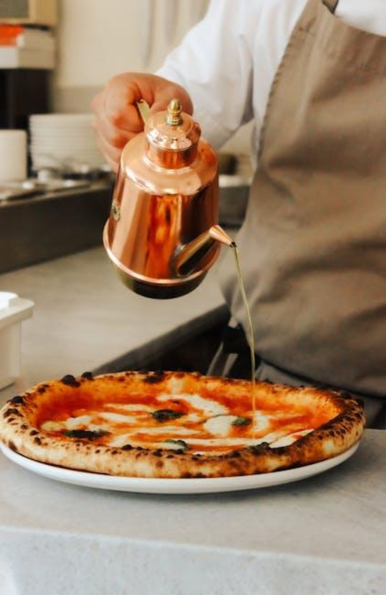 Servire_le_polpette_di_pollo_piccata_SrGF1peeE4 - Confidenze24 Source: damla selen demir - pexels - Gourmet pizza topped with fresh olive oil in a professional kitchen setting.