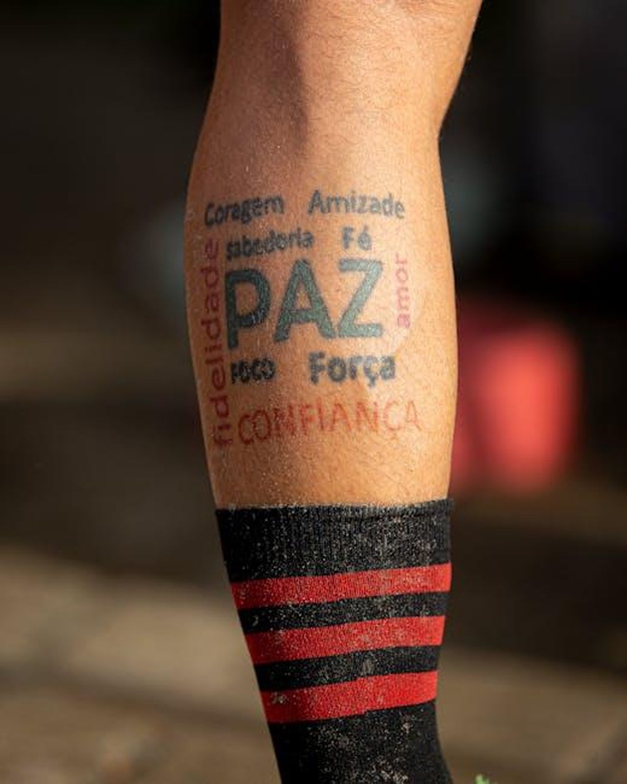 Significato_dei_tatuaggi_di_Paris_OlpPgd7dRt - Confidenze24 Source: Eduardo Holanda - pexels - A leg tattoo featuring various words emphasizing peace and strength, captured in warm lighting.