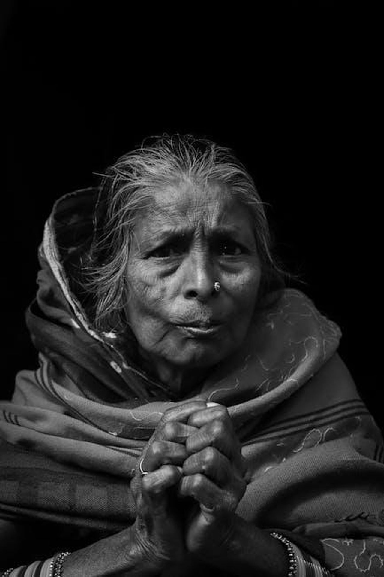 Storie_emozionanti_allinterno_dello_show_rj1DrZiD0L - Confidenze24 Source: Harshi Rateria - pexels - Black and white portrait of a senior woman with hands clasped, in traditional attire.