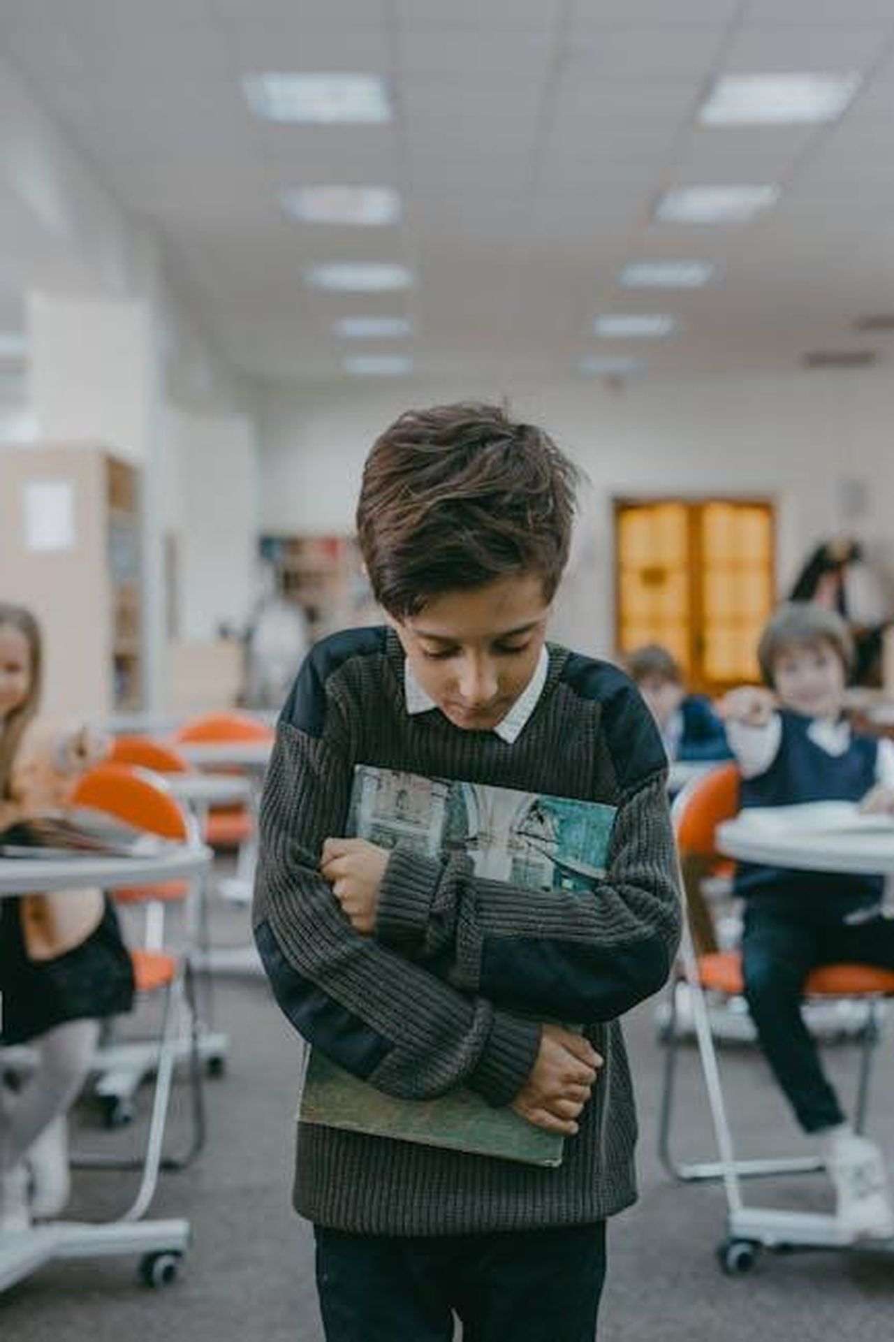Tatum_ONeal_e_gli_Abusi_dei_Genitori_h78e8u8lN4 - Confidenze24 Source: Mikhail Nilov - pexels - Sad boy holding books tightly, showing signs of bullying and isolation in a classroom.