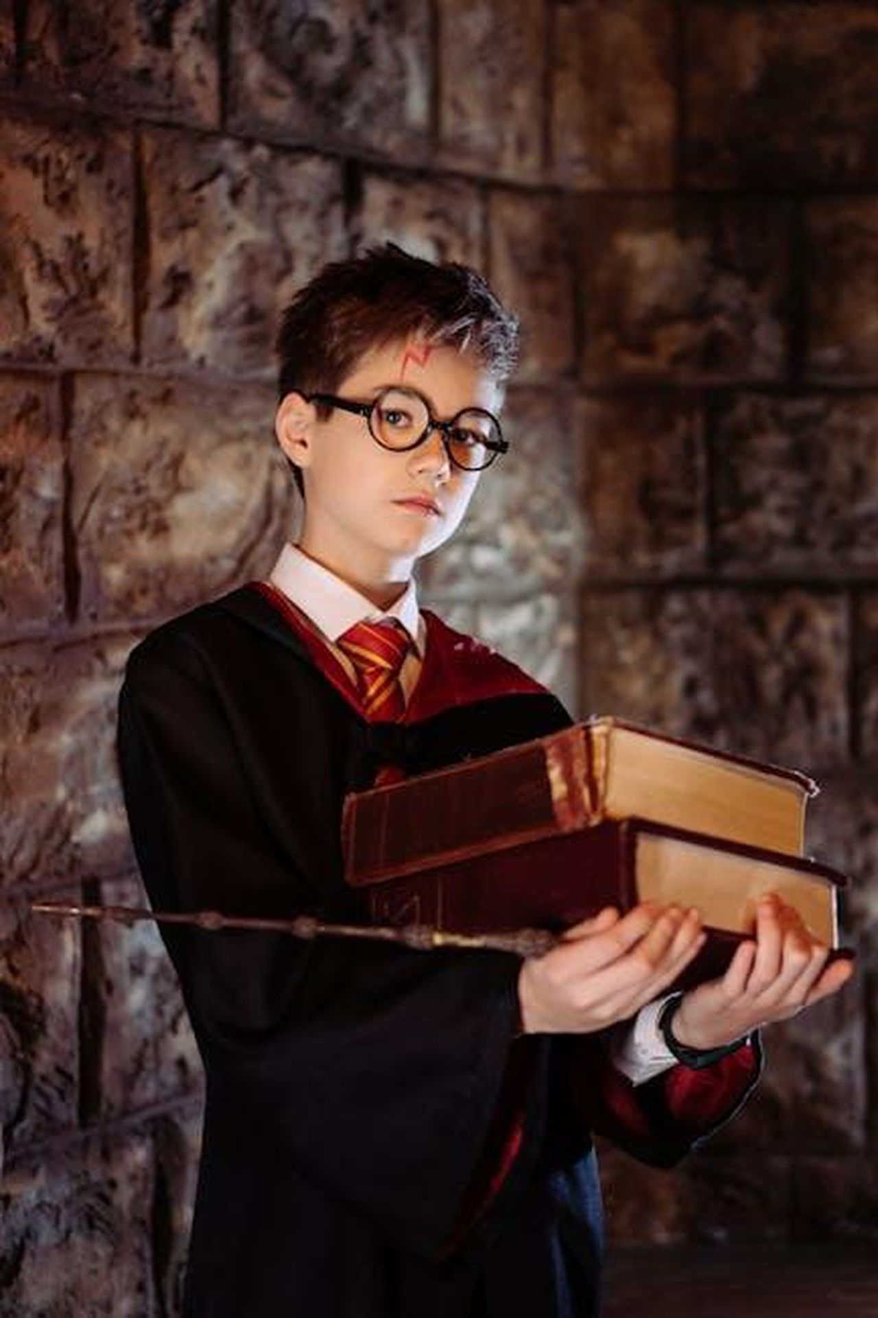 Temi_importanti_da_esplorare_attraverso_la_lettura_vVD0DFziKZ - Confidenze24 Source: Mikhail Nilov - pexels - A young wizard in costume holds books and a wand, evoking a fantasy theme.