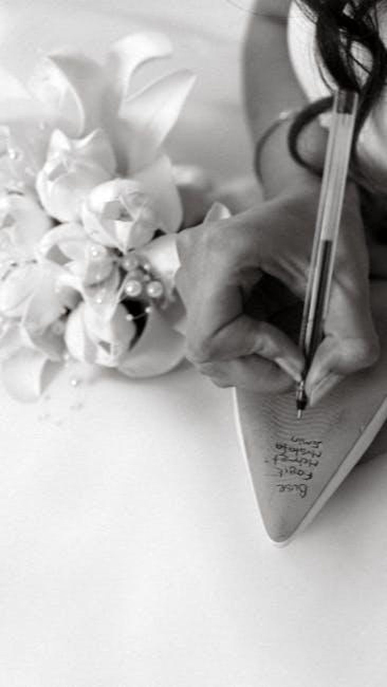Tendenze_audaci_nei_nomi_di_mezzo_6T7jfx6Dcp - Confidenze24 Source: thecactusena - pexels - A bride writes names on her wedding shoe beside a bouquet, symbolizing good luck.