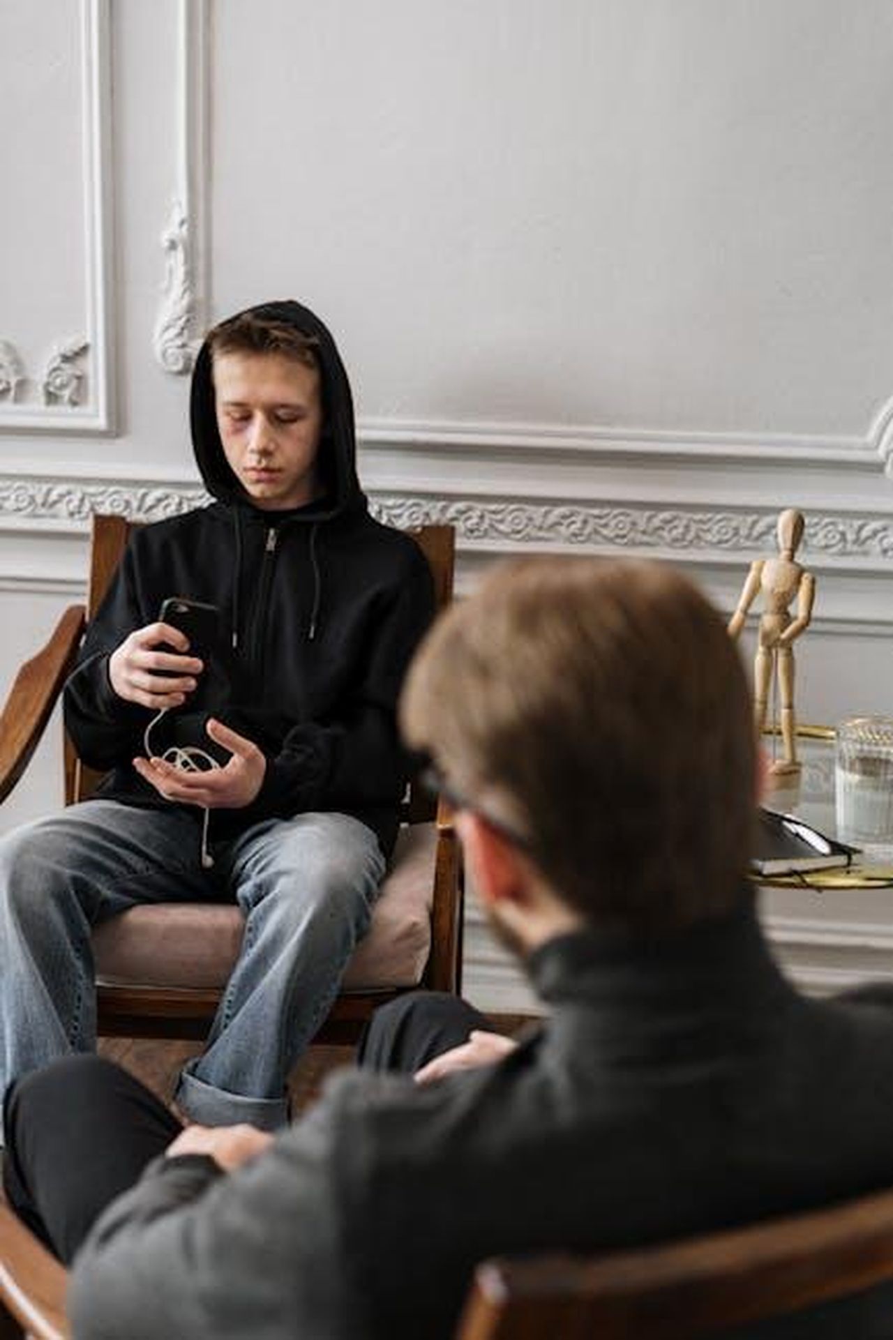 Teoria_dei_fan_Tommy_in_difficolt_con_la_sua_sessualit_3MCF3iMheh - Confidenze24 Source: cottonbro studio - pexels - A teenage boy in a black hoodie during a therapy session, using his phone.