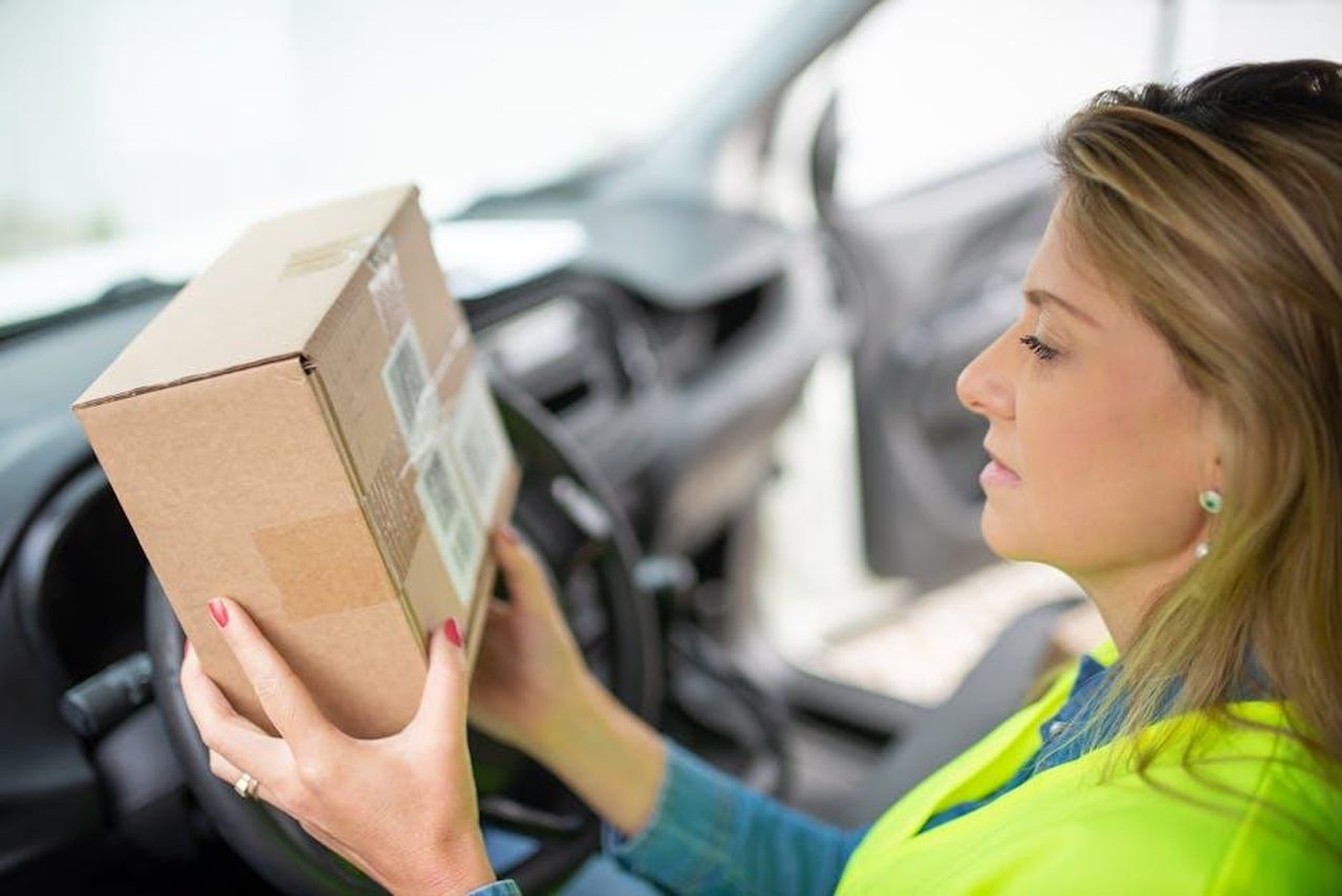 Testimonianze_di_utenti_soddisfatti_ElwXANMjpN - Confidenze24 Source: Kampus Production - pexels - A woman courier checks a delivery package while seated inside a car, ready for distribution.