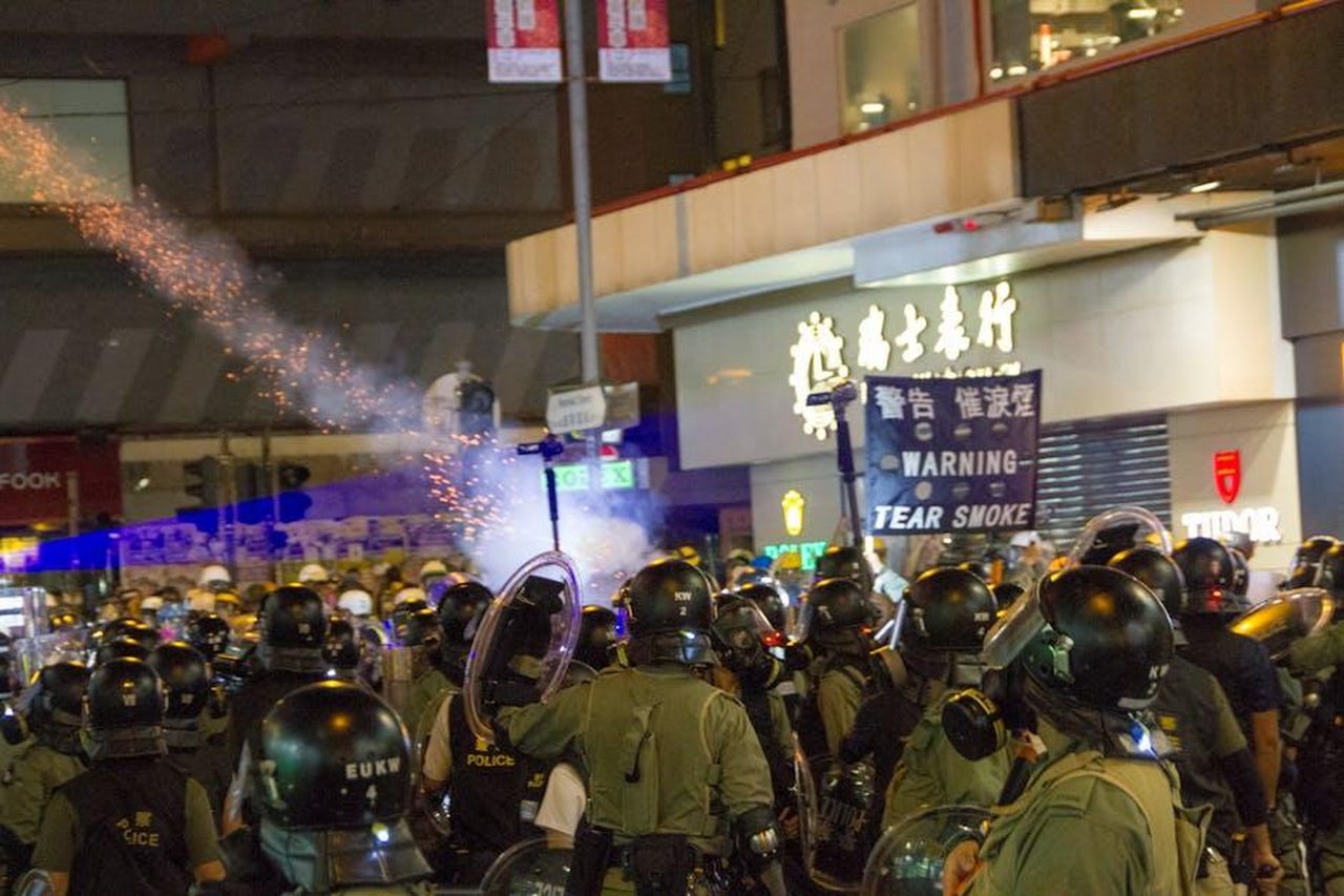 Tim_Scott_Difende_Trump_YSj5BZlxEL - Confidenze24 Source: LT Chan - pexels - Riot police in tactical gear facing a public protest at night with tear gas.
