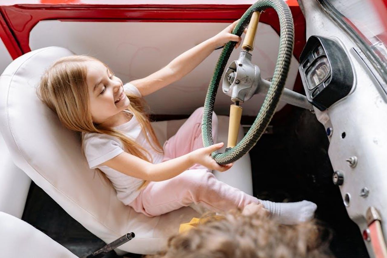 Tina_prima_di_Corrie_J8KGM7yvXx - Confidenze24 Source: Yan Krukau - pexels - Joyful child playing driver in a vintage car, capturing the essence of childhood imagination and joy.