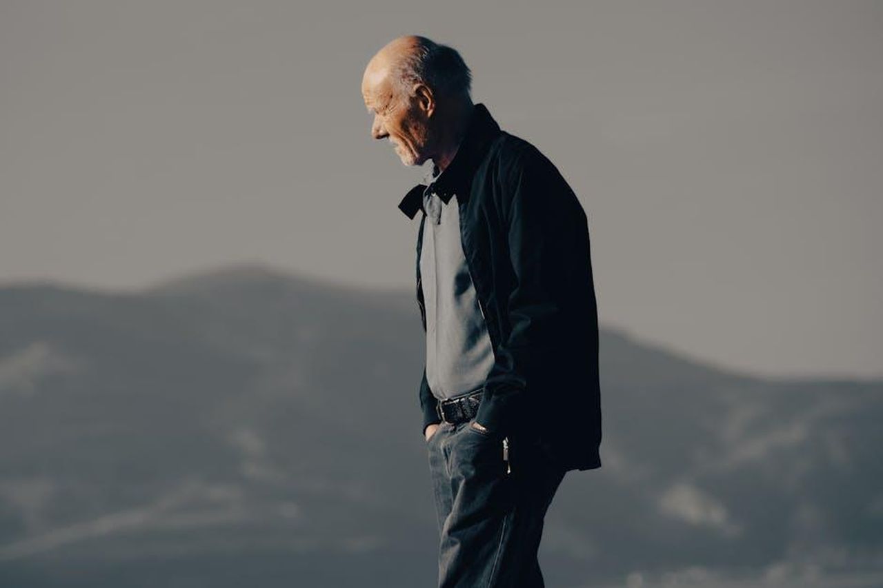 Torvill_e_Dean_si_ritirano_dmJMj4gU8f - Confidenze24 Source: Enes Beydilli - pexels - Senior man walking with hands in pockets against mountain backdrop during the day.