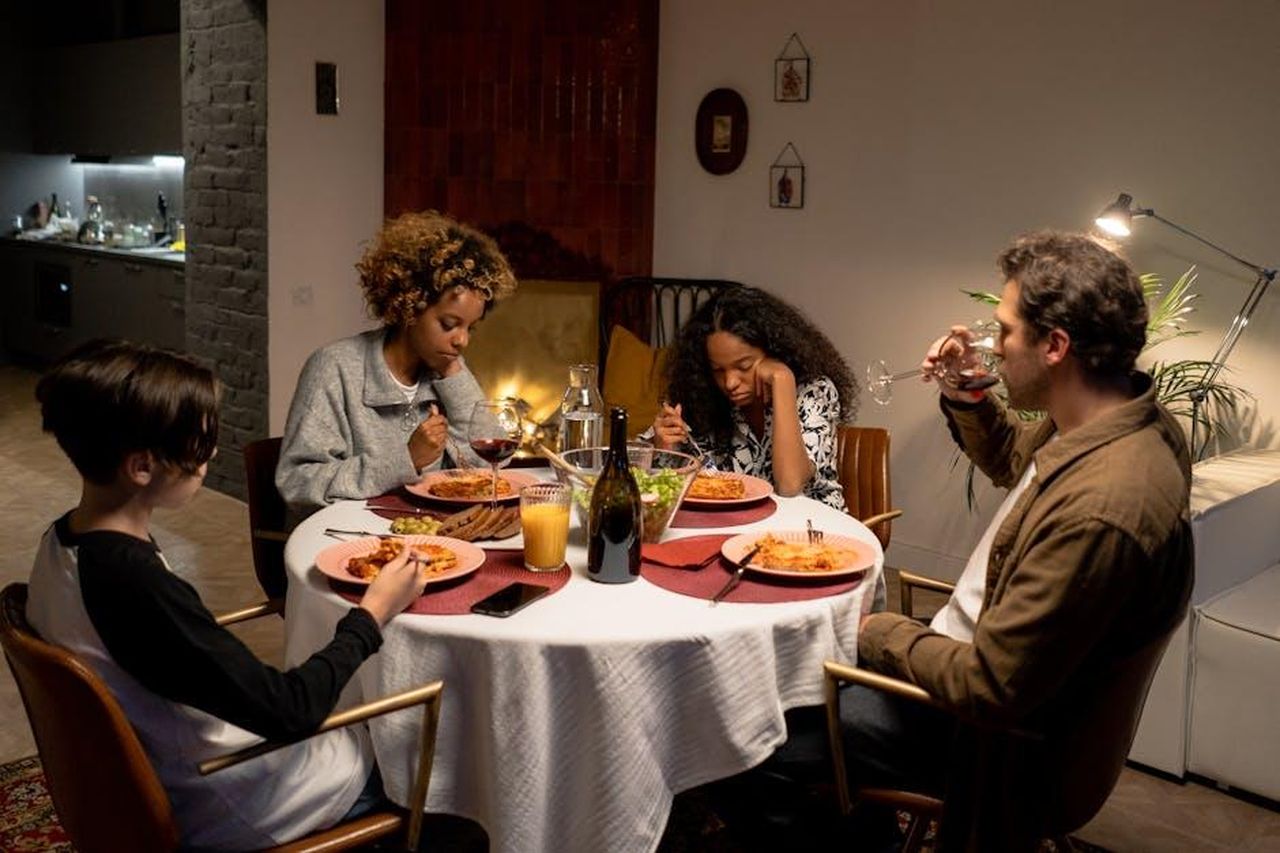 Totalmente_vergognoso_K6N9POPb0r - Confidenze24 Source: cottonbro studio - pexels - A diverse family shares a dinner of pasta and wine around a cozy indoor table setting.