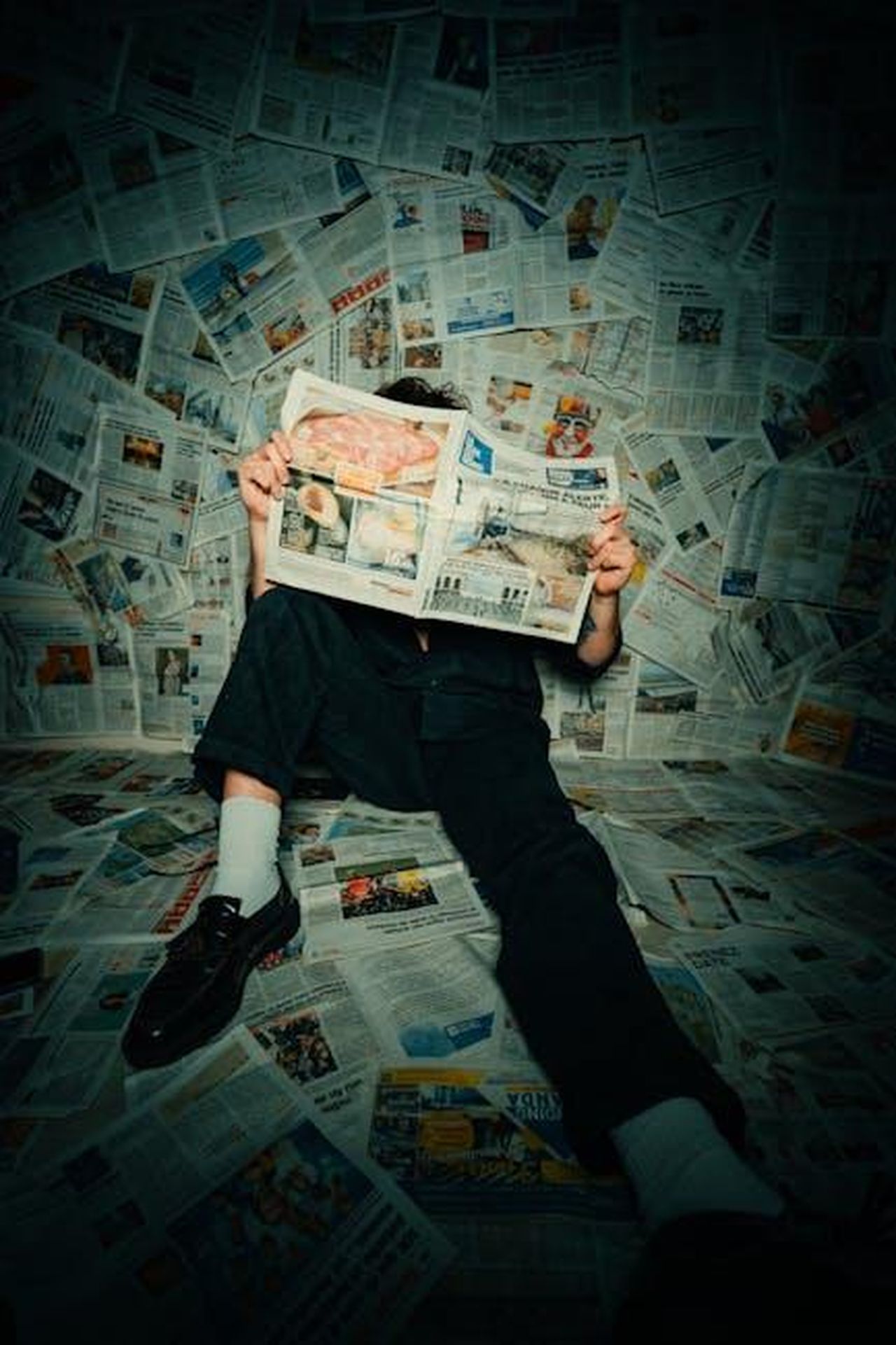Tributi_a_Lester_Holt_dai_Colleghi_5QfV8C3cQO - Confidenze24 Source: Léo Gilmant - pexels - Person sitting on floor covered with newspapers, reading in a creative setup.