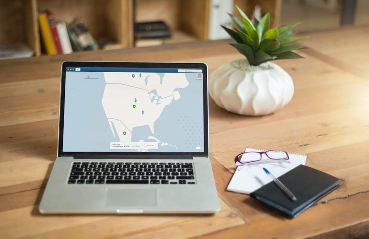 Un_amore_lontano_dai_riflettori_ARBPUVTjBR - Confidenze24 Source: Kevin Paster - pexels - A laptop displaying VPN software sits on a wooden desk with a notepad and plant offering a secure workspace vibe.