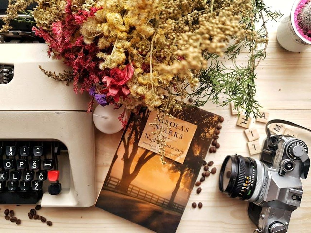 Un_aneddoto_romantico_il_guanto_e_lanello_9br148nAbx - Confidenze24 Source: Ena Marinkovic - pexels - A cozy vintage workspace featuring a typewriter, camera, book, and dried flowers.