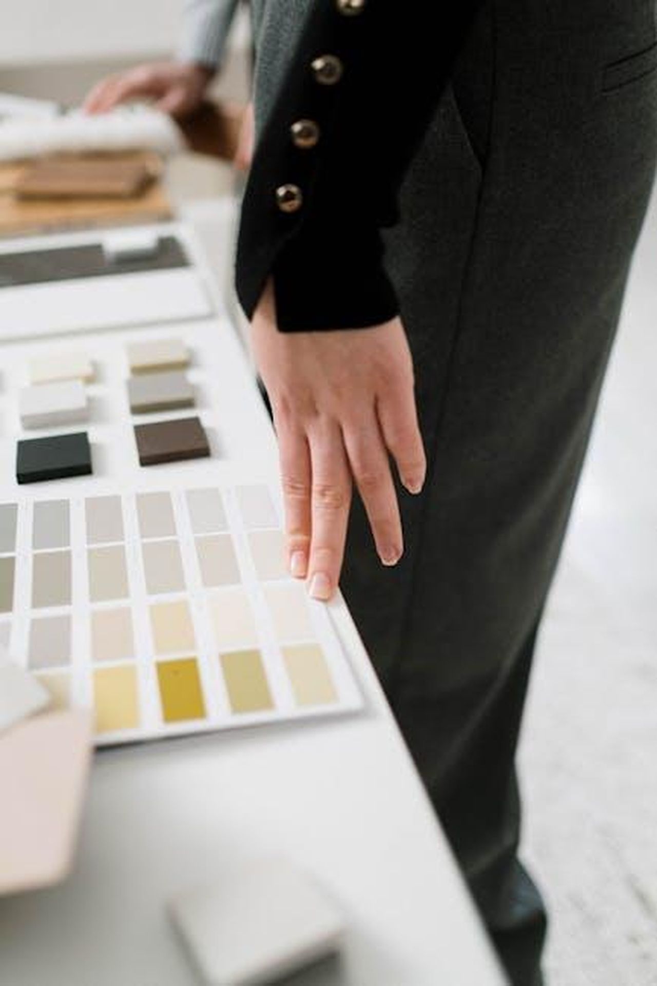 Un_appuntamento_che_parla_di_moda_Del_Friscos_Grille_2oNLeszFx8 - Confidenze24 Source: cottonbro studio - pexels - A close-up of a designer's hand with color palette samples on a white table, showcasing material selection.