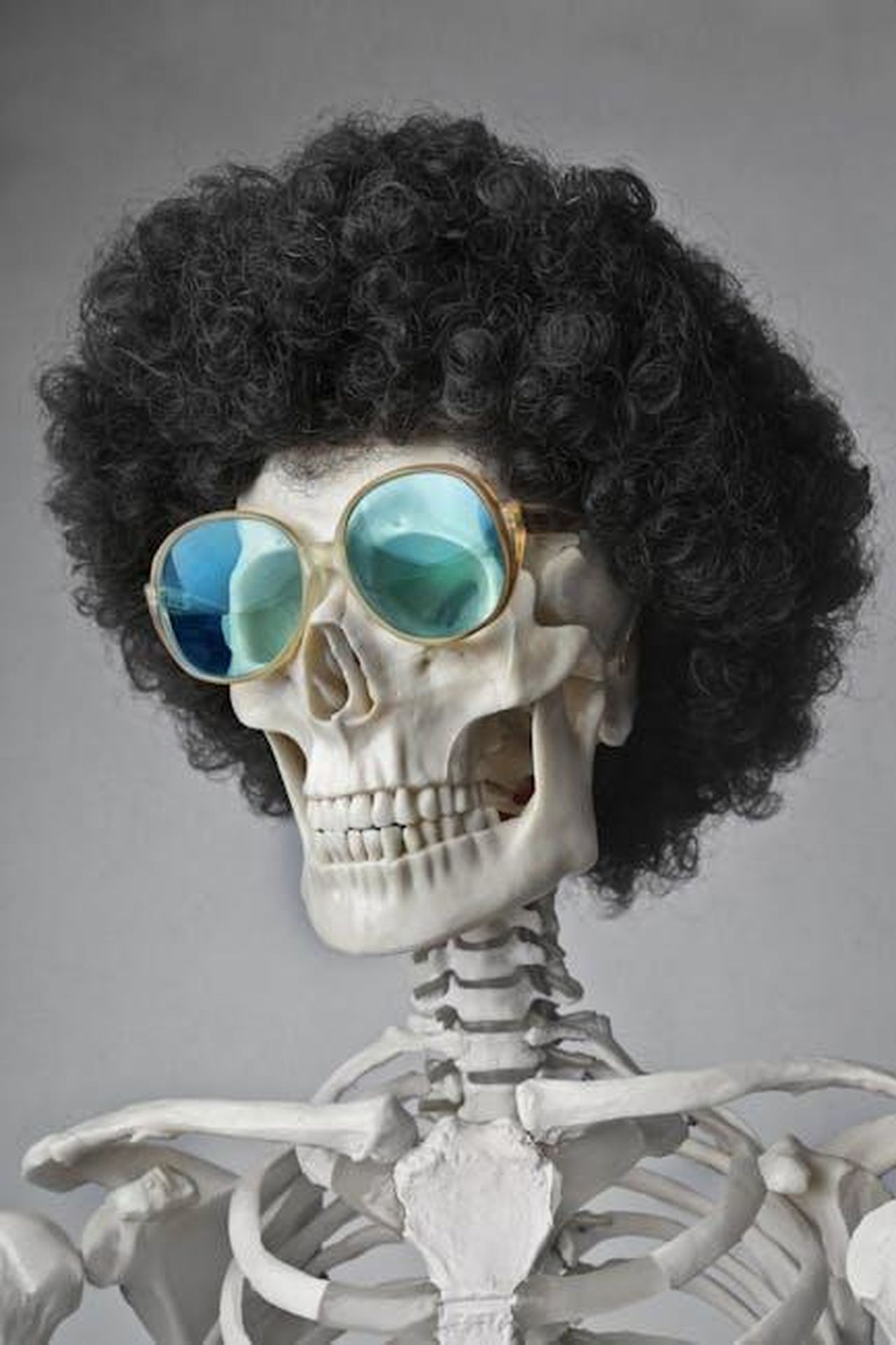 Un_errore_di_moda_J6v37bJTUH - Confidenze24 Source: Andrea Piacquadio - pexels - A skeleton wearing an afro wig and sunglasses, set against a gray background.