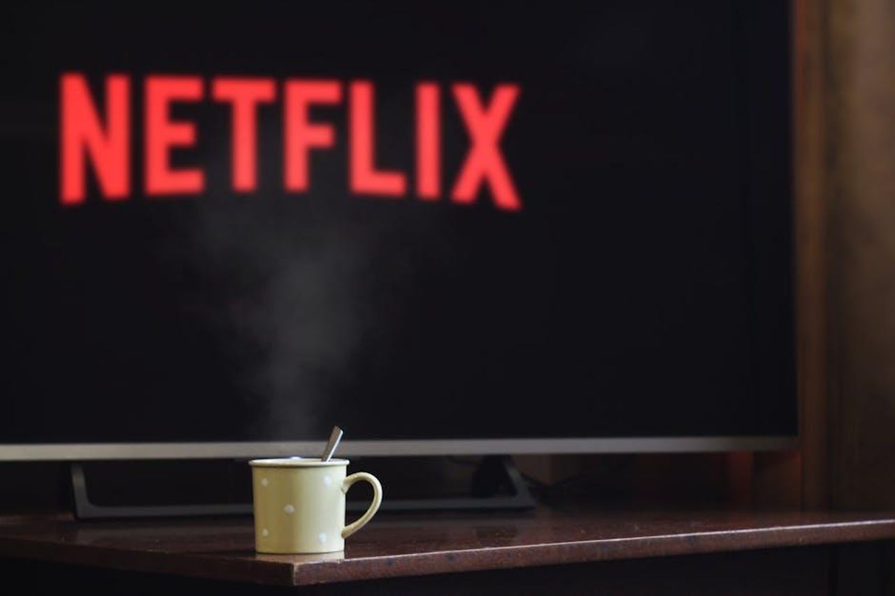 Un_nuovo_spinoff_Boston_Blue_HIiRO6cnAm - Confidenze24 Source: John-Mark Smith - pexels - A steaming mug on a table in front of a TV displaying Netflix, creating a cozy indoor atmosphere.