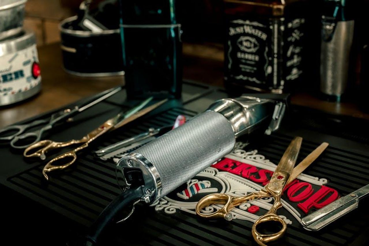 Un_prodotto_intramontabile_8mFXAv1sde - Confidenze24 Source: Elchino portrait - pexels - Close-up of barber tools including electric razor and scissors on a salon counter.
