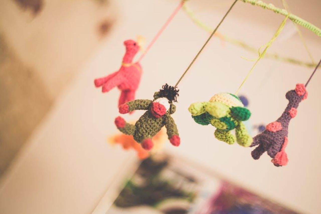 Una_nursery_per_la_piccola_Palma_aUhON0Oni3 - Confidenze24 Source: Markus Spiske - pexels - Colorful knitted animal toys hanging from a nursery mobile creating a playful atmosphere.