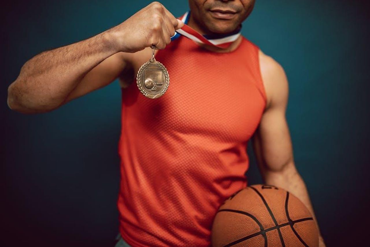 Una_vittoria_superba_9ZBG0V3Hg4 - Confidenze24 Source: RDNE Stock project - pexels - Man holding a medal and basketball, showcasing achievement in sports.