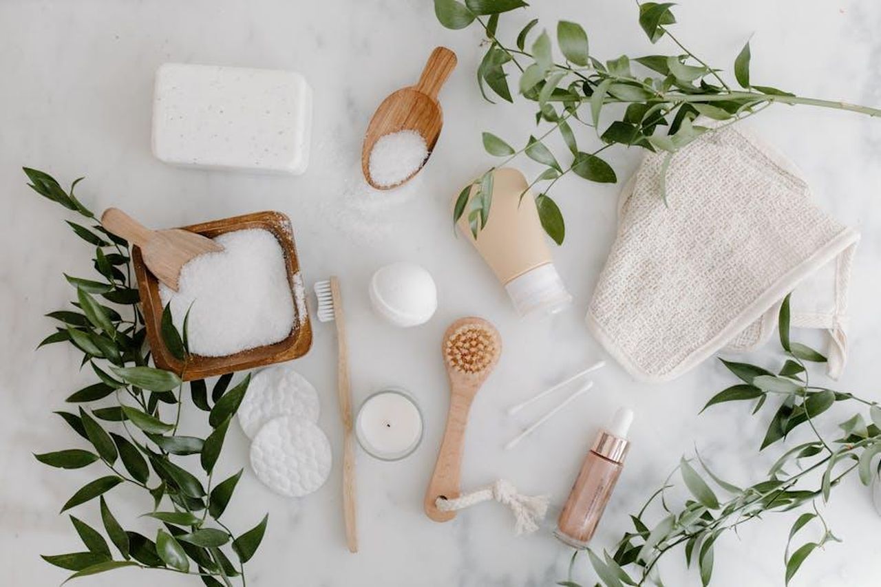 Unalternativa_economica_e_di_qualit_Doz9vQMtPg - Confidenze24 Source: Tara Winstead - pexels - Elegant flat lay of organic bath essentials including soap, brush, and salts with greenery.
