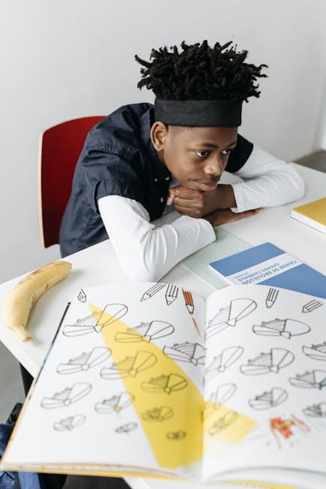 Uninfanzia_normale_lontano_dai_riflettori_Q6rMh0Yvo5 - Confidenze24 Source: Pavel Danilyuk - pexels - A young boy attentively studies in a classroom with open books on the desk.