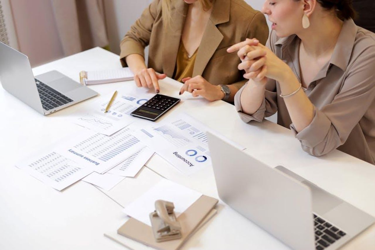 Versione_dei_fiduciari_2BHBIQJYGc - Confidenze24 Source: Artem Podrez - pexels - Two professionals collaborating on financial documents in a modern office setting.