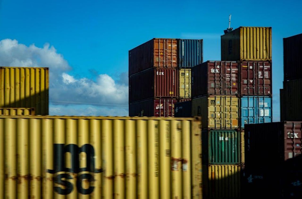 Voci_di_trasferimento_in_Europa_DU2MNTZQtL - Confidenze24 Source: Magda Ehlers - pexels - A vibrant display of stacked cargo containers against a clear blue sky.