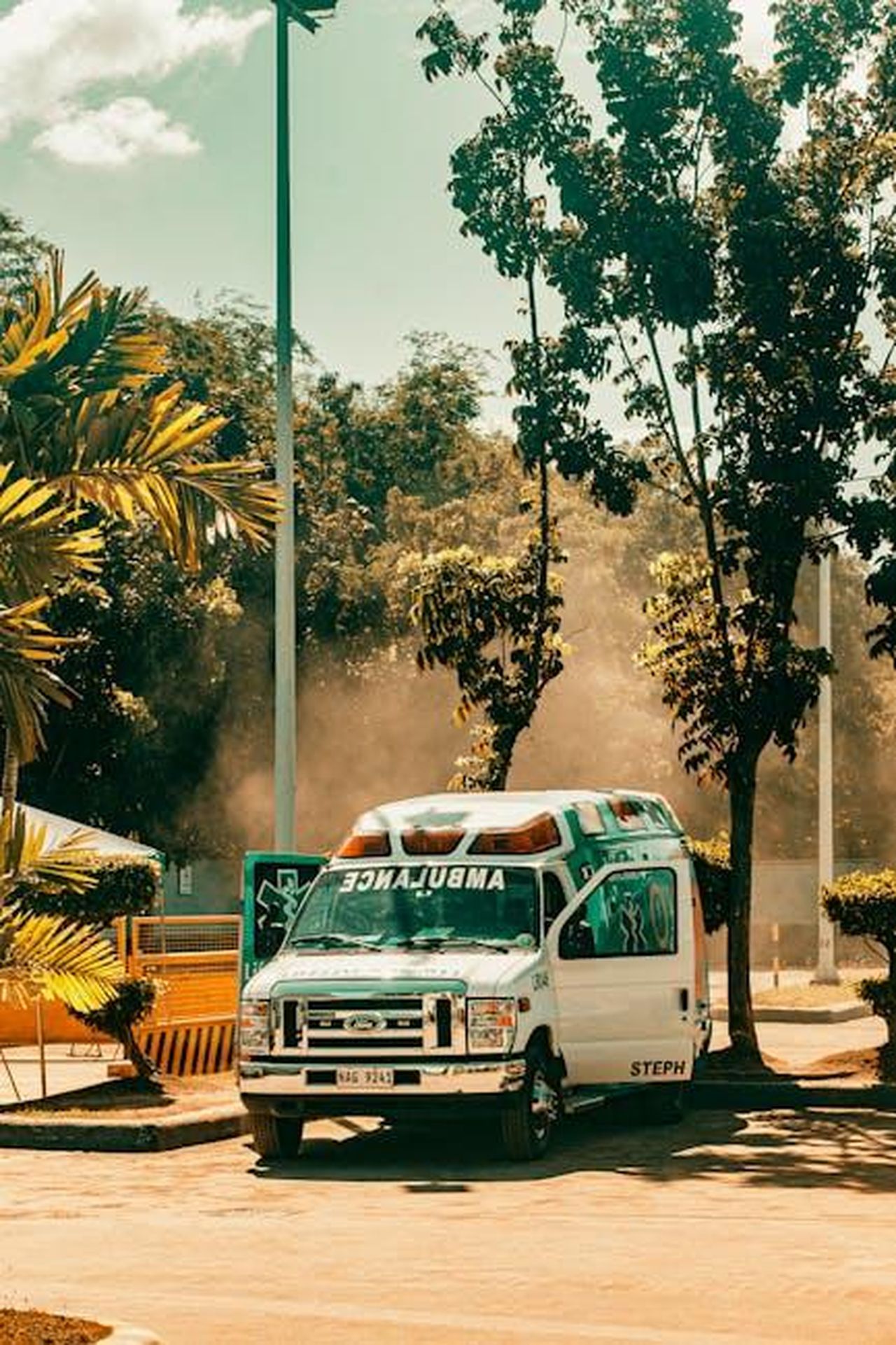 Wendy_in_difficolt_prima_del_test_Y1xuAEkq7i - Confidenze24 Source: Nothing Ahead - pexels - A parked ambulance in a sunlit outdoor area surrounded by trees and sunny weather.