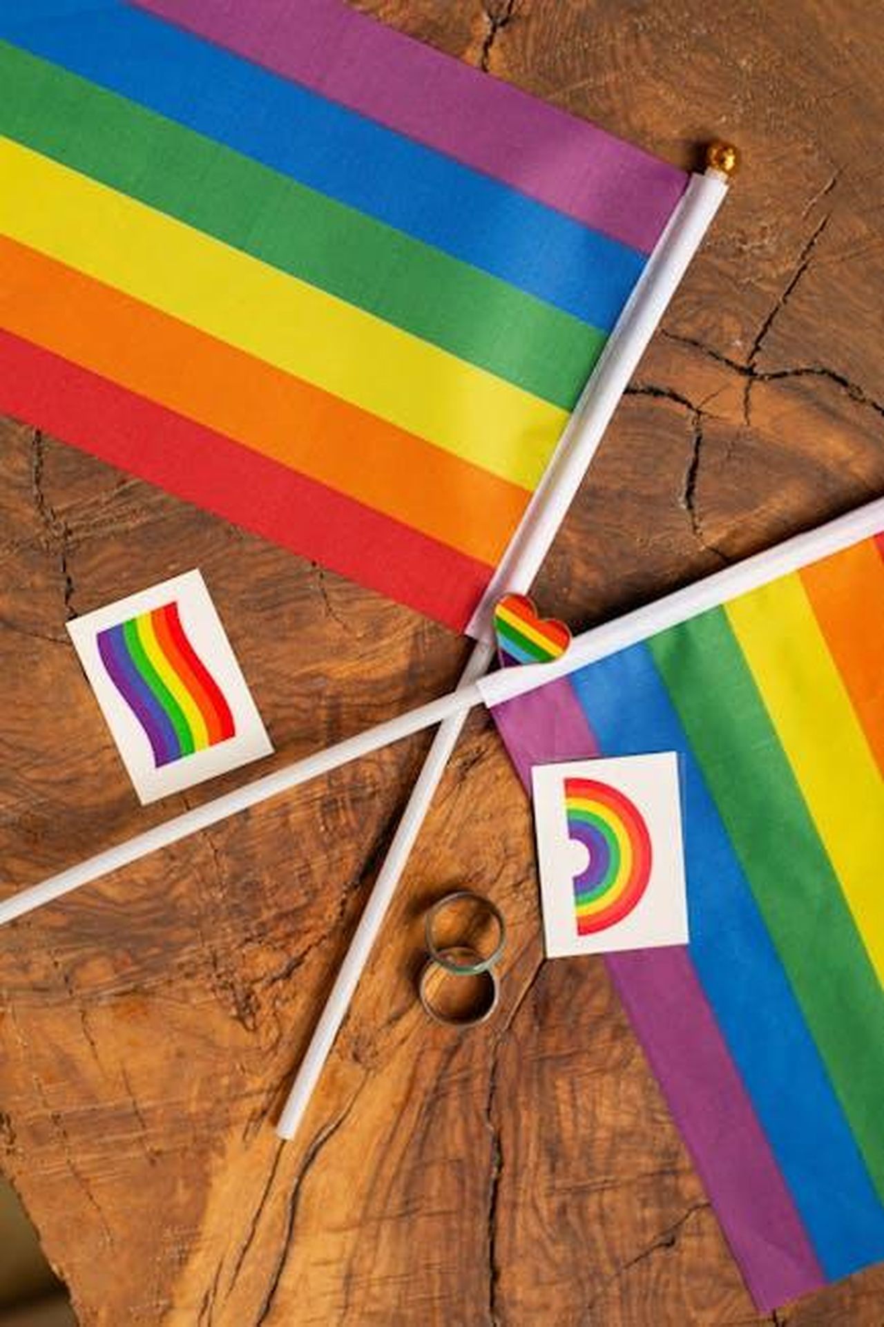 Zaya_Wade_attivista_per_i_diritti_transgender_9DK6XRTFx8 - Confidenze24 Source: Monstera Production - pexels - Rainbow pride flags and symbols arranged on a rustic wooden table, representing LGBTQ+ pride and unity.