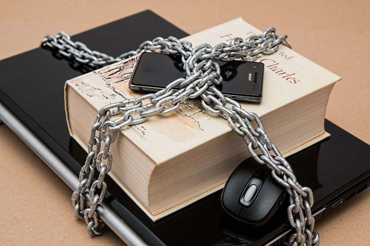 _molto_riservato_sulla_sua_vita_personale_TXRXkJ25aV - Confidenze24 Source: Pixabay - pexels - Chain-locked book, phone, and laptop symbolizing digital and intellectual security.