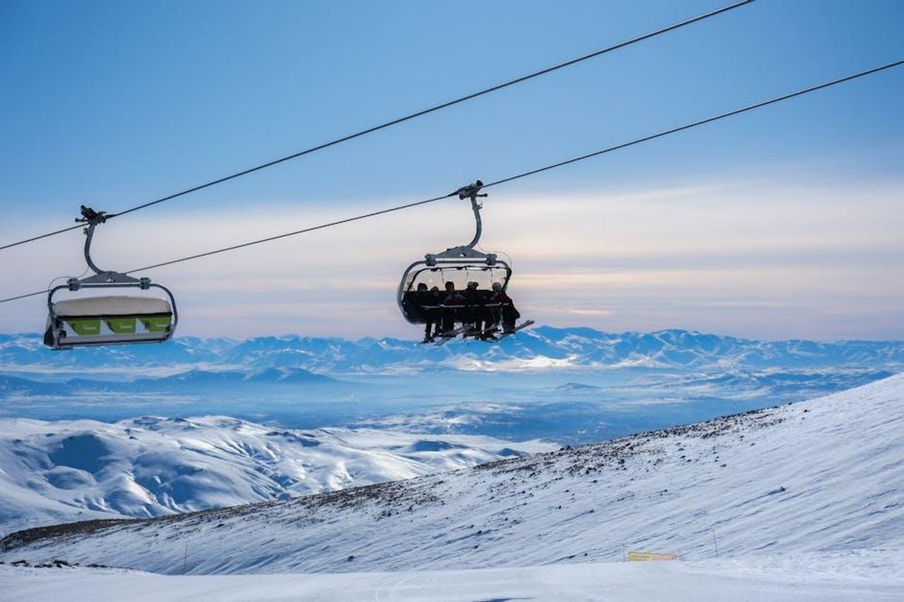Attivit_sulla_neve_e_relax_5zSOcWsxkW - Confidenze24 Source: Osman Arabacı - pexels - A scenic view of a ski resort cable car gliding over snowy mountains at sunset in Turkey.