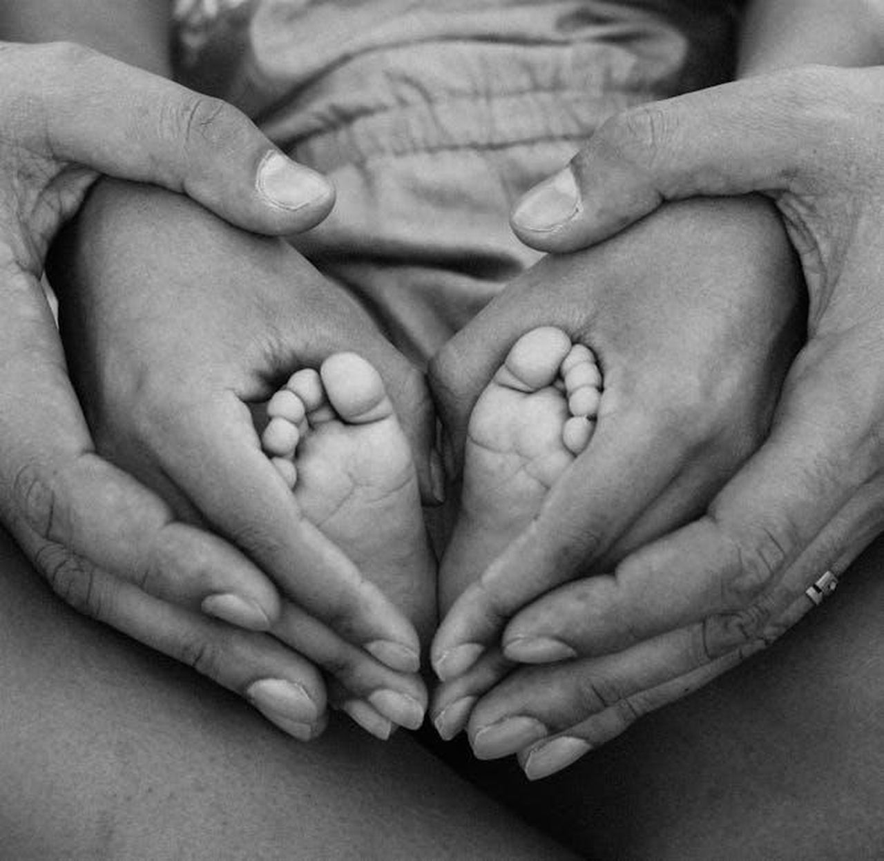 Collegarsi_con_altri_genitori_di_bambini_transgender_pisZzVwyA6 - Confidenze24 Source: Alexandro David - pexels - Black and white photo of adult hands cradling baby feet, symbolizing family love and connection.
