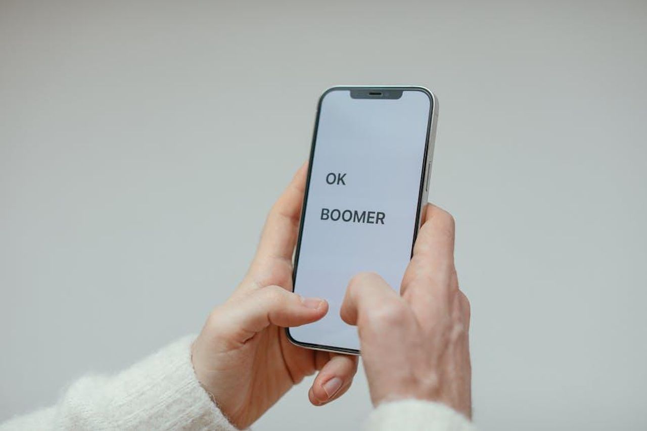 Denise_si_unisce_al_divertimento_online_OuoxhKTEB6 - Confidenze24 Source: Cup of Couple - pexels - Close-up of a person holding a smartphone displaying 'OK Boomer' against a plain background.