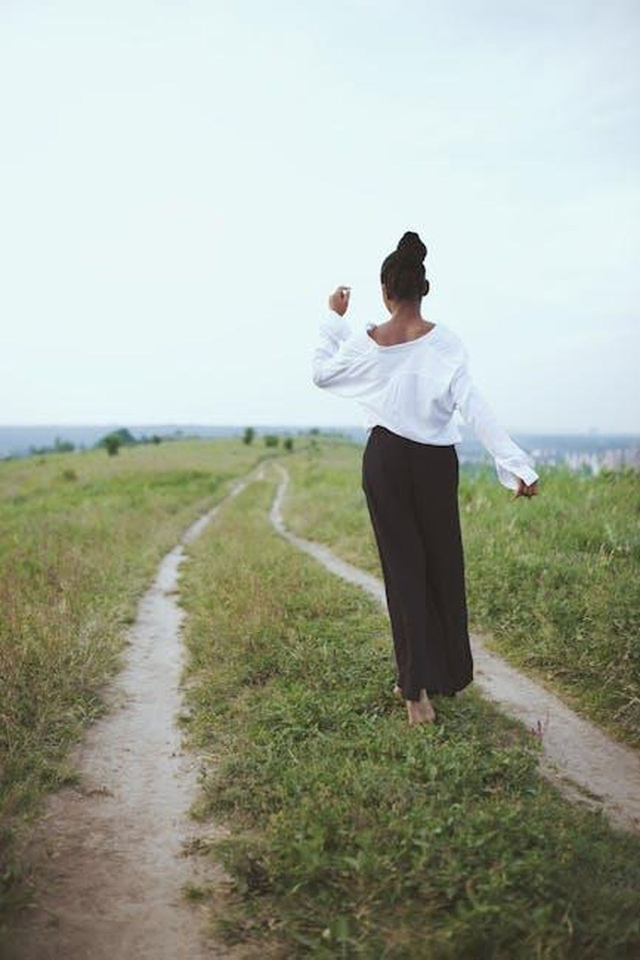 Il_desiderio_di_Harry_di_riconnettersi_YOCqXTXja9 - Confidenze24 Source: Aidi Tanndy - pexels - A woman walks barefoot on a grassy rural path, embracing nature and solitude.