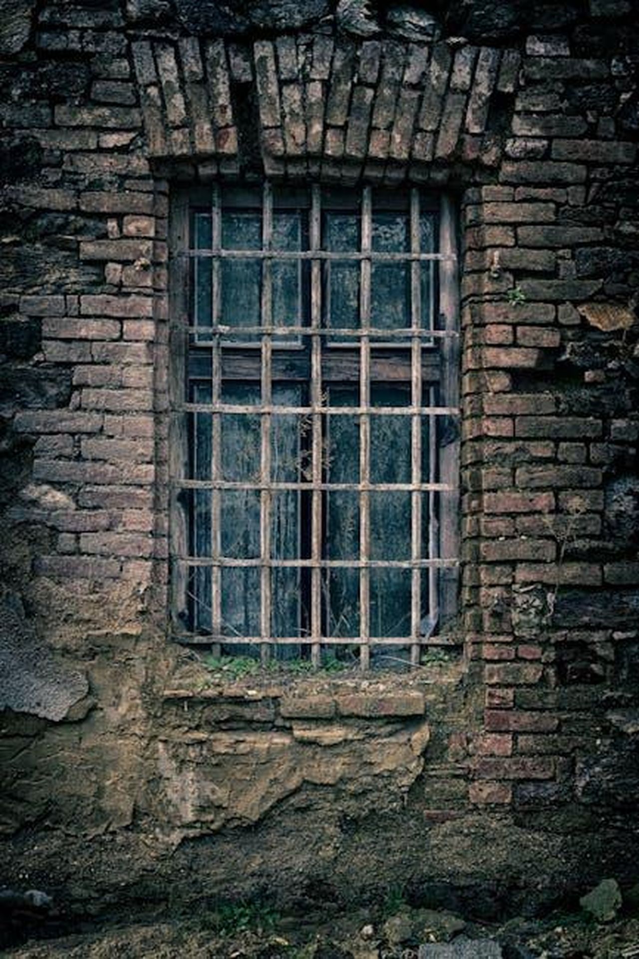 Il_ritorno_di_Dirty_Den_oudNlAyglZ - Confidenze24 Source: Pixabay - pexels - A moody close-up of an old brick wall featuring a barred window, capturing a sense of nostalgia.