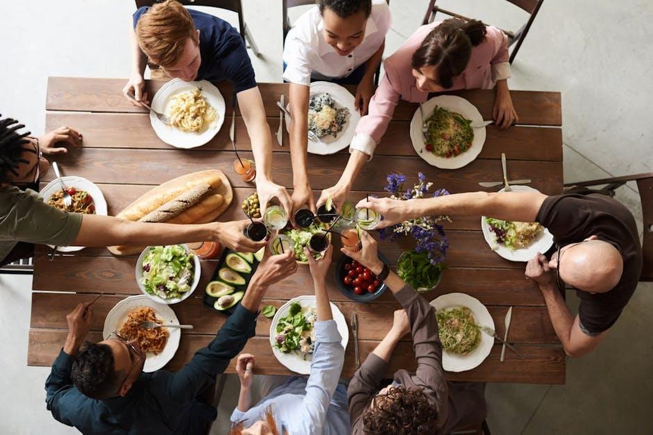 Il_suo_consiglio_per_ospitare_cene_SUPevQnrT4 - Confidenze24 Source: fauxels - pexels - A vibrant group cheers over a delicious meal, showcasing friendship and togetherness.