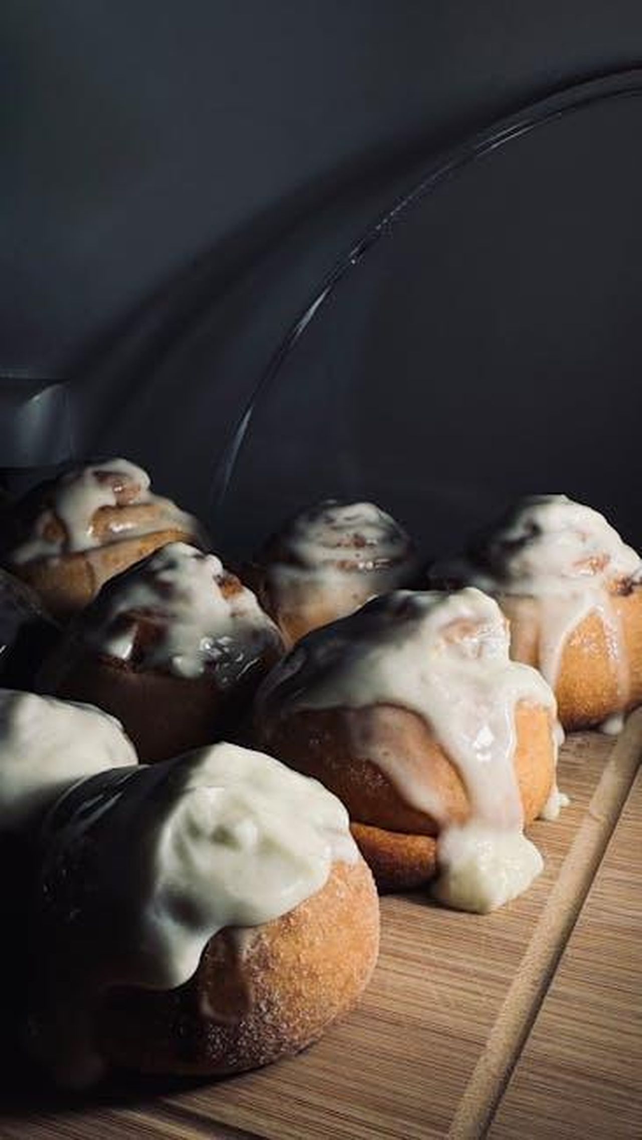 Il_tocco_finale_glassa_di_zucchero_a_velo_5lHUY59wux - Confidenze24 Source: Alex Koval - pexels - Close-up of warm, freshly baked cinnamon rolls covered in creamy white icing on a wooden board.