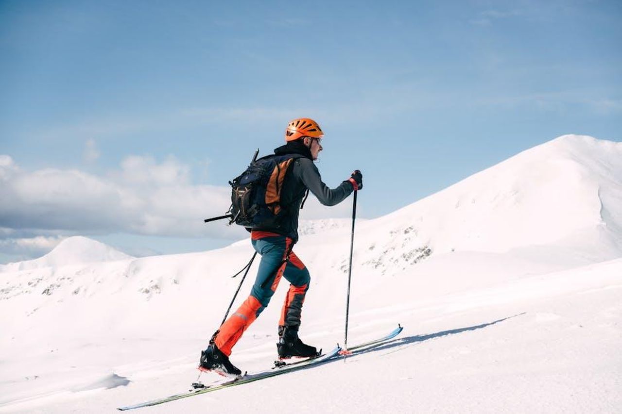 La_salute_di_Re_Carlo_e_le_preoccupazioni_del_pubblico_Lg1oAzILoE - Confidenze24 Source: Jordi Costa Tomé - pexels - Skier climbing a snowy mountain in bright attire with poles, under a clear blue sky.