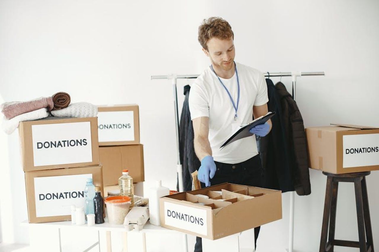 Le_accuse_di_Sophie_Chandauka_contro_Harry_Y16a8ZAPoG - Confidenze24 Source: Gustavo Fring - pexels - A man organizing donations in boxes inside a room with various supplies on a table.