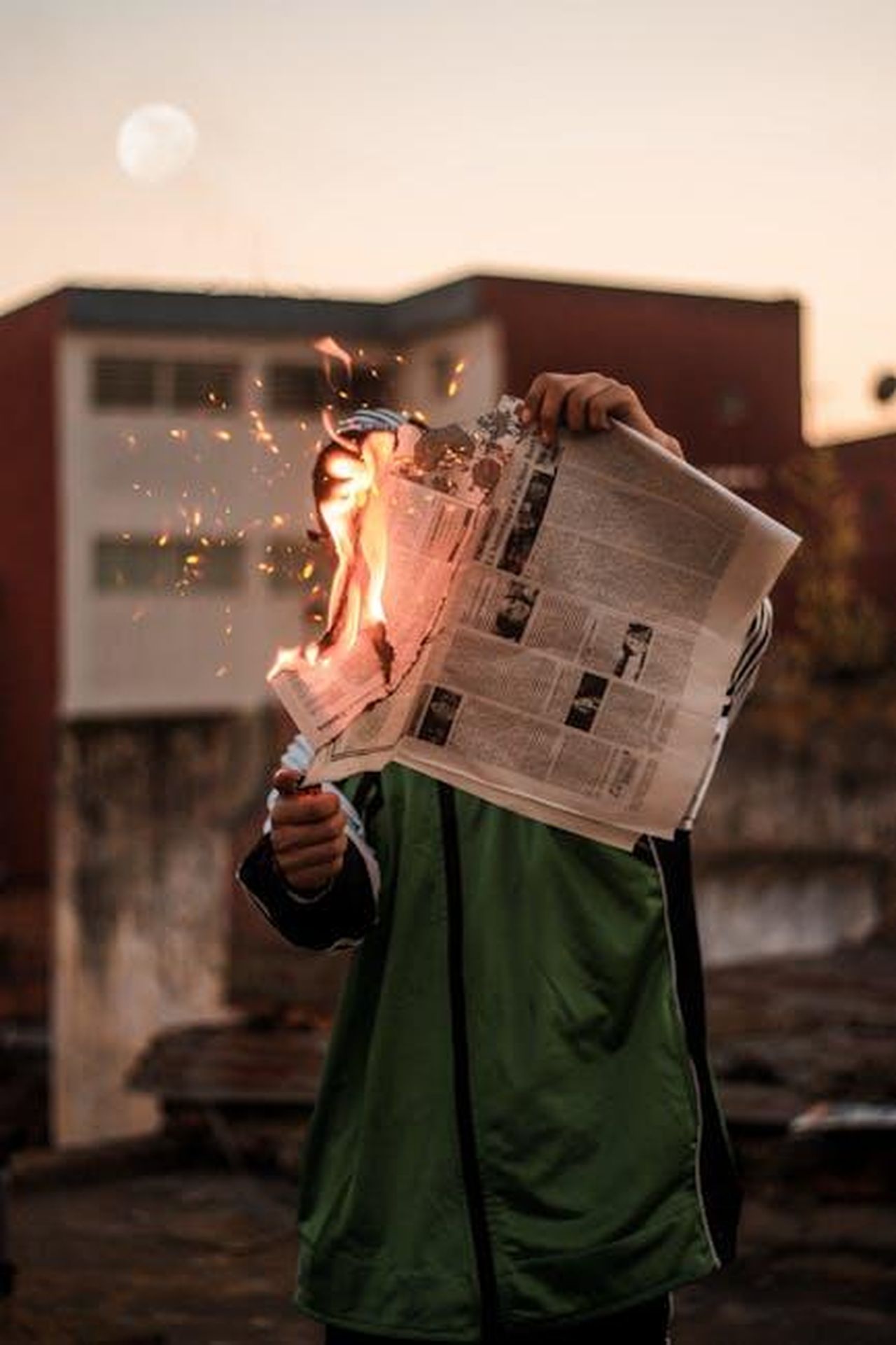 Le_controversie_attorno_a_Sophie_Chandauka_9K1mZRIRgd - Confidenze24 Source: mustafa youssoufi - pexels - A person holds a burning newspaper on the street at twilight, creating dramatic visuals.