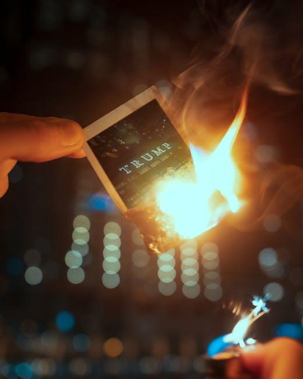 Le_polemiche_dellanno_scorso_VAd7cD39Fs - Confidenze24 Source: Josh Hild - pexels - Photo of a hand holding a burning card with Trump text, captured at night.