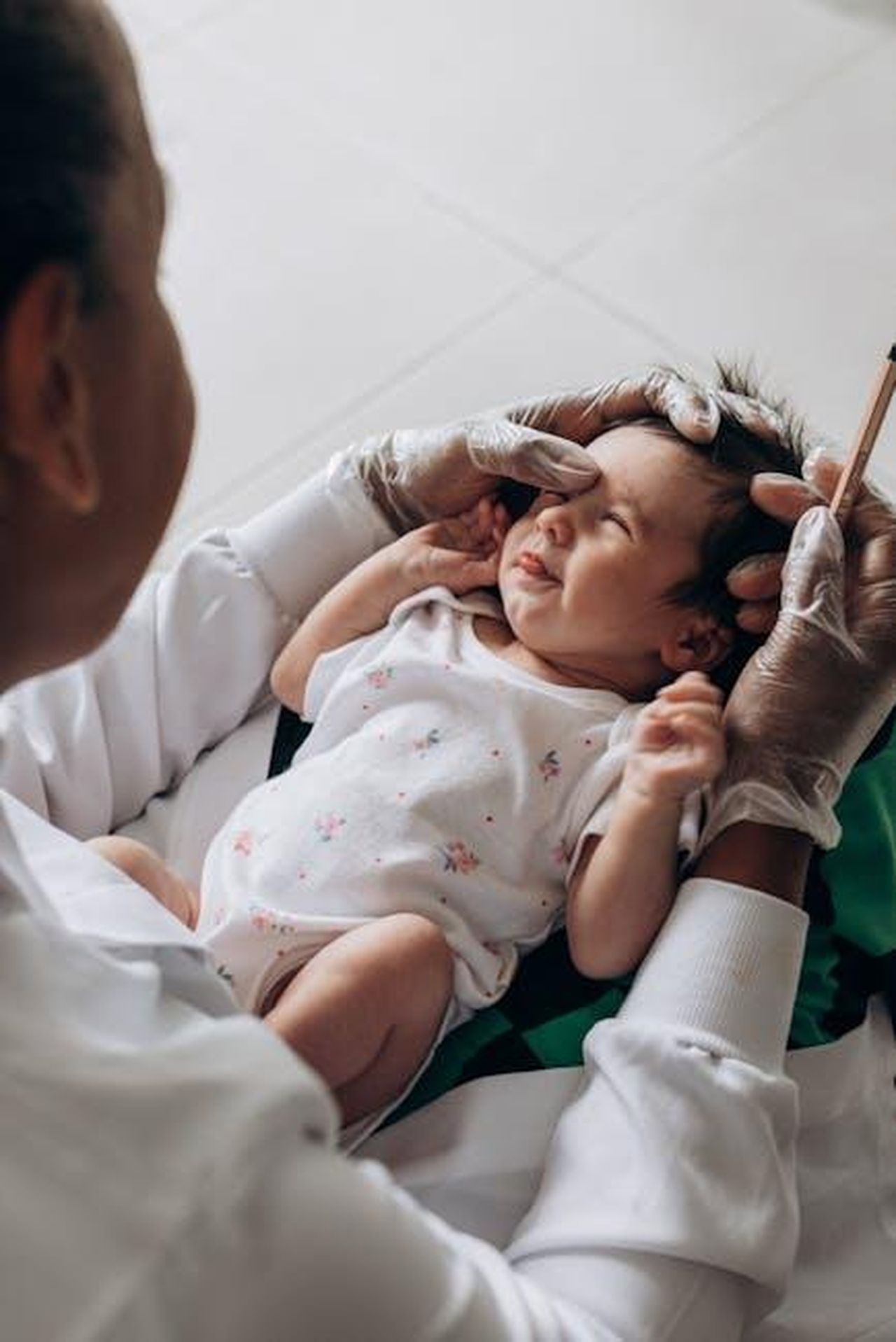 Le_sfide_di_Kim_con_lesame_baby_bar_NsoqPG7wEn - Confidenze24 Source: Jonathan Borba - pexels - A healthcare professional examines a newborn baby indoors, demonstrating care and attention.