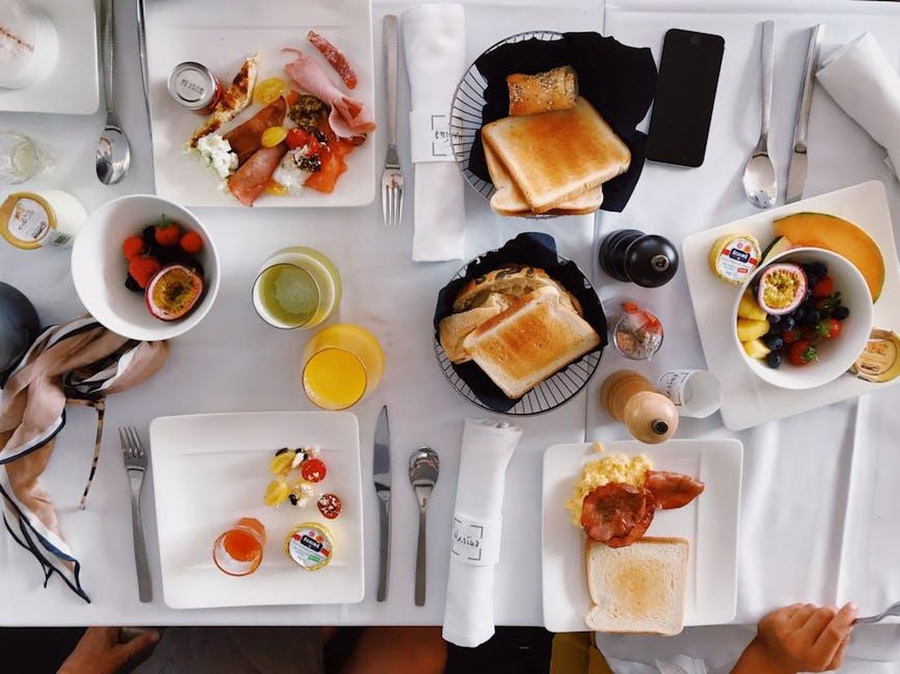 Limportanza_del_brunch_e_dei_bagel_XU9iM1VWxN - Confidenze24 Source: julie aagaard - pexels - Flatlay of an elegant brunch setup with fruits, toasts, and beverages on a white tablecloth.